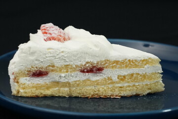 One small Japanese strawberry shortcake on a stylish Japanese plate on a black cloth on a white table