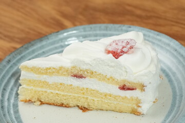 One small Japanese strawberry shortcake on a stylish Japanese plate on a wooden tray on a black cloth on a white table