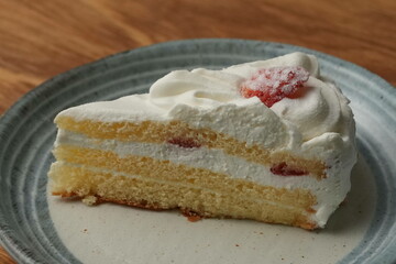 One small Japanese strawberry shortcake on a stylish Japanese plate on a wooden tray on a black cloth on a white table