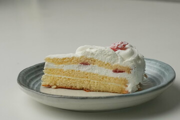 One small Japanese strawberry shortcake on a stylish Japanese plate on a white table