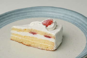 One small Japanese strawberry shortcake on a stylish large plate on a white table