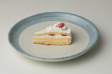 One small Japanese strawberry shortcake on a stylish large plate on a white table