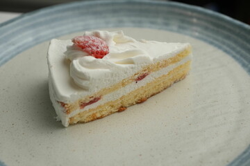 One small Japanese strawberry shortcake on a stylish large plate on a white table