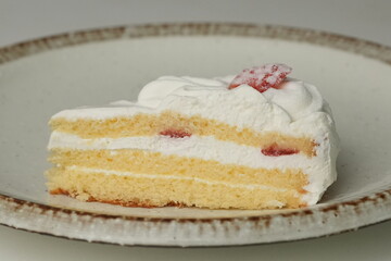 One small Japanese strawberry shortcake on a stylish large plate on a white table