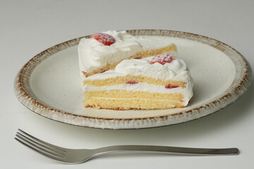 Two Japanese strawberry shortcakes and a large fork on a stylish large plate on a white table