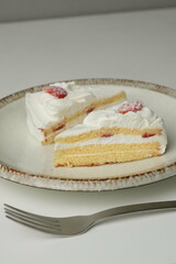 Two Japanese strawberry shortcakes and a large fork on a stylish large plate on a white table
