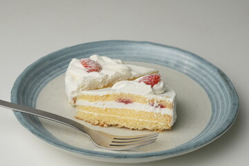 Two Japanese strawberry shortcakes and a large fork on a stylish large plate on a white table