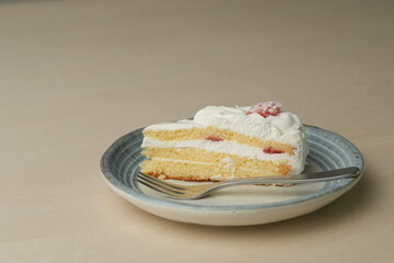 Japanese strawberry shortcake and fork on each stylish large and small plate on a wooden table