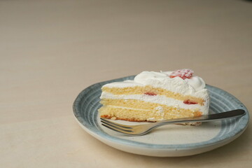 Japanese strawberry shortcake and fork on each stylish large and small plate on a wooden table