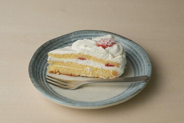 Japanese strawberry shortcake and fork on each stylish large and small plate on a wooden table
