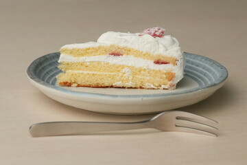 Japanese strawberry shortcake and fork on each stylish large and small plate on a wooden table