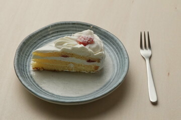 Japanese strawberry shortcake and fork on each stylish large and small plate on a wooden table