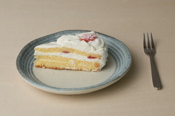 Japanese strawberry shortcake and fork on each stylish large and small plate on a wooden table