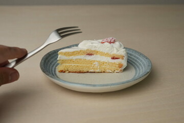 Japanese strawberry shortcake and fork on each stylish large and small plate on a wooden table
