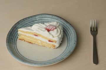 Japanese strawberry shortcake and fork on each stylish large and small plate on a wooden table