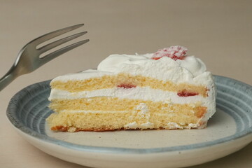 Japanese strawberry shortcake and fork on each stylish large and small plate on a wooden table
