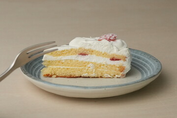 Japanese strawberry shortcake and fork on each stylish large and small plate on a wooden table