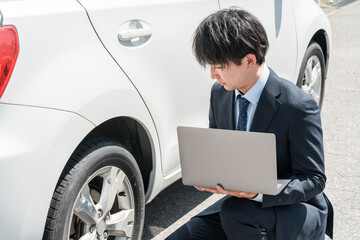 中古車を査定する営業マン・中古車査定士のスーツ姿の若いアジア人男性
