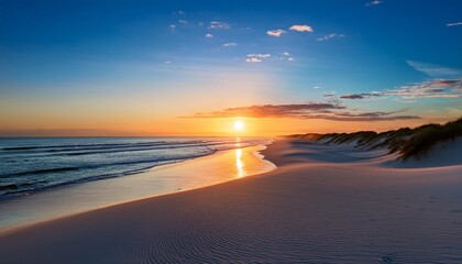 Obraz premium Sunset Over a Serene Beach With White Sand Dunes Stretching Into the Distance, While the Calm Ocean Reflects the Vibrant Colors of the Evening Sky and Gently Lapping Waves