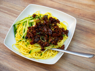 Noodles with sliced cucumber and sauce with mushrooms and meat. Delicious Chinese noodle lunch