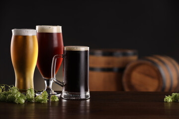 Glasses with different types of beer and fresh hops on wooden table in bar. Space for text