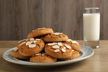 Tasty cookies with almond flakes and milk on wooden table, closeup