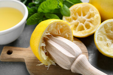 Wooden squeezer, lemons, juice and mint on grey table, closeup