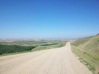 Fototapeta premium Panoramic view of a hilly prairie, under a bright blue sky.
