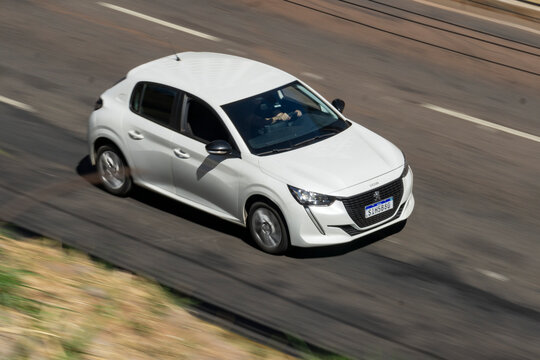 White Peugeot 208 in movement, Compact hatchback car in city street