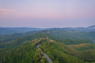 Aerial view of countryside winding  road passing through the green forest and mountain in Thailand.