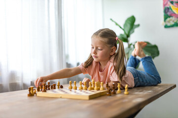 5-year-old girl plays mini chess, carefully planning her next move in a fun learning moment