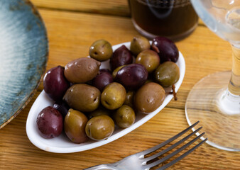 Bunch of large black olives and green olives with pits served in bowl