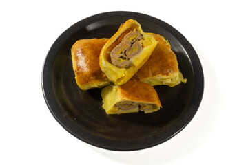 Bolen Pisang is a light dish made from bananas covered in rolled sheets of pastry dough. Various toppings such as cheese and chocolate. Served in black plate on white background. Selective focus image