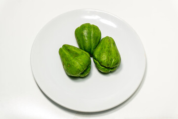 Sechium edule or fresh chayote on white plate isolated on white background. Food ingredient, vegetarian cuisine, organic farm plant