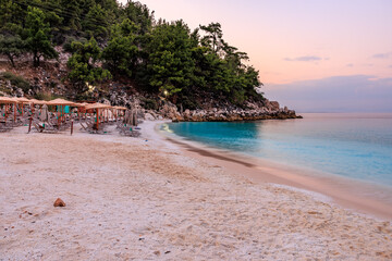 A beach with a blue ocean and a few umbrellas