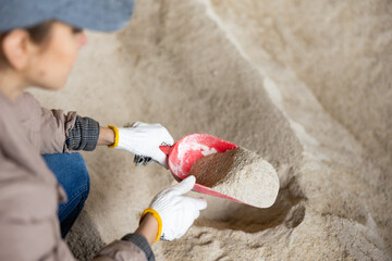 Confident woman owner of dairy farm checking quality of corn flour for feeding livestock animals in farm storage area © JackF