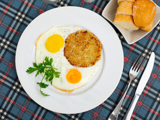 Fried vegetable pancake griddle-cake tortillas made from grated zucchini pulp are laid out on plate and complemented sunny-side up eggs, and decorated with sprig of parsley
