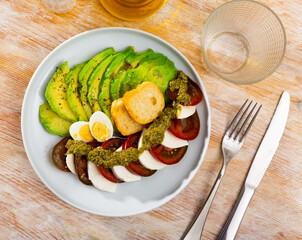 Appetizing caprese salad with mozzarella served with avocado and eggs on platter