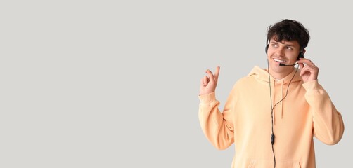 Male technical support agent pointing at something on grey background with space for text