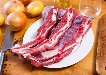 Raw beef ribs on the kitchen table along with other ingredients for making a delicious lunch or dinner