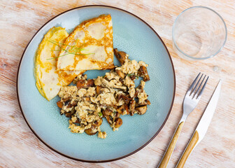 Appetizing omelet with mushrooms and asparagus served with pancakes on plate