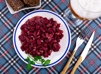 Restaurant serves light and low-calorie lunch - stewed boiled vegetables, boiled kidney beans with glass of bear, slices of rye bread.