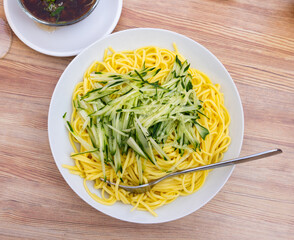 Chinese noodles with sliced cucumber and meat sauce with mushrooms. Delicious asian noodles for lunch