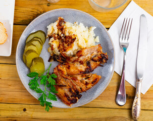 Delicious fried pork with potatoes and pickled cucumber served on platter