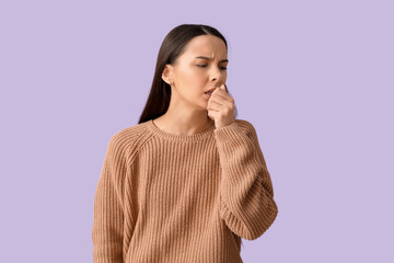Beautiful young woman suffering from sore throat on lilac background