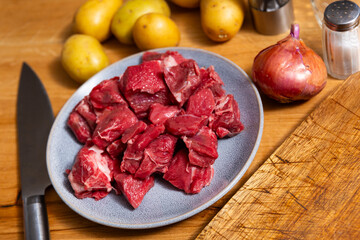 Raw beef veal meat tenderloin lie next to spices - process of cooking homemade festive dish. Pieces of raw veal on table, meat processing before frying.