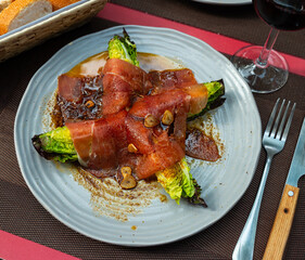 Delicious Spanish cabbage dish with bacon and sauce on a plate. Appetizing appetizer Cogollos con jamon