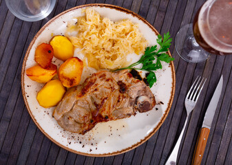 Appetizing piece of fried pork with marinated cabbage and potatoes