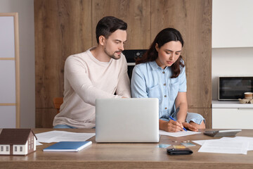 Young couple in debt writing down something at home. Bankruptcy concept
