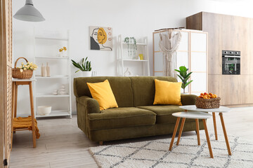 Stylish interior of living room with comfortable sofa and basket of apricots on coffee table